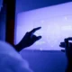 Person vor einem blauen holografischen Bildschirm mit einer schematischen Darstellung eines Gesichts als Symbol für KI in Neurowissenschaft und kognitiver Stimulation.