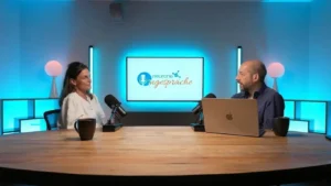 Dr. Genny Lubrini im Gespräch bei NeuronUP Talks in einem Aufnahmestudio mit Mikrofonen und einem Bildschirm mit dem Text Teatro Talks im Hintergrund.