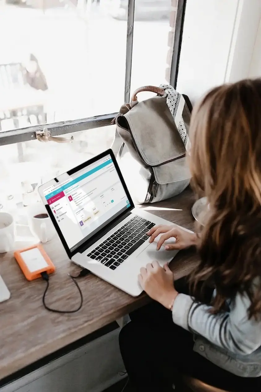 Person an einem Schreibtisch, die an einem Laptop mit der Tele-Rehabilitationsoberfläche von NeuronUP arbeitet, beleuchtet von natürlichem Licht