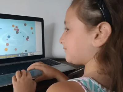 Mädchen sitzt vor einem Laptop, trägt ein Stirnband und arbeitet mit NeuronUP.