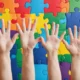 Kinderhände vor einem Hintergrund mit Puzzleteilen in leuchtenden Farben zum Welt-Autismus-Tag.