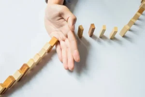 Hand hält eine Reihe bunter Holzklötze auf, die eine Kurve bilden und Resilienz angesichts von Widrigkeiten symbolisieren.