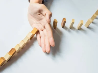 Hand hält eine Reihe bunter Holzklötze auf, die eine Kurve bilden und Resilienz angesichts von Widrigkeiten symbolisieren.