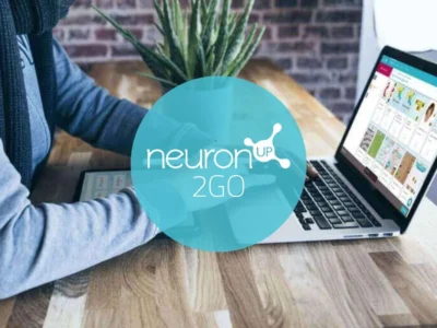 Ältere Person nutzt zu Hause ein Tablet für von NeuronUP2GO angeleitete Übungen zur kognitiven Rehabilitation; häusliche Umgebung mit sichtbarem Logo.
