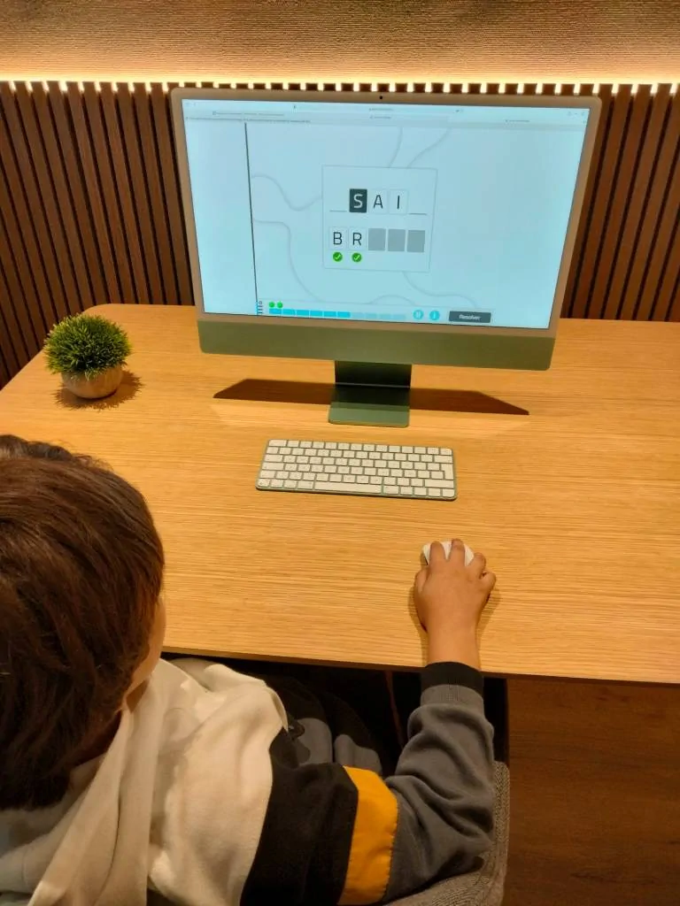 Enfant assis devant un ordinateur effectue des exercices de langage avec NeuronUP pendant une séance TEL