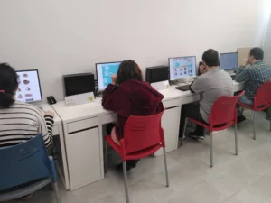 Groupe de personnes atteintes du syndrome de Down travaillant sur la stimulation cognitive avec NeuronUP dans un espace de classe moderne.