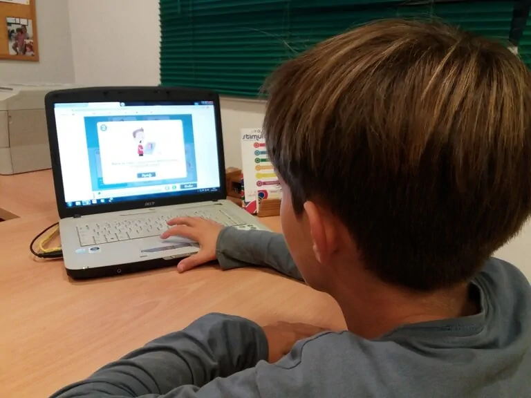 Enfant devant un ordinateur portable, concentré sur l'écran de NeuronUP, montrant une activité de stimulation cognitive pour TSA.