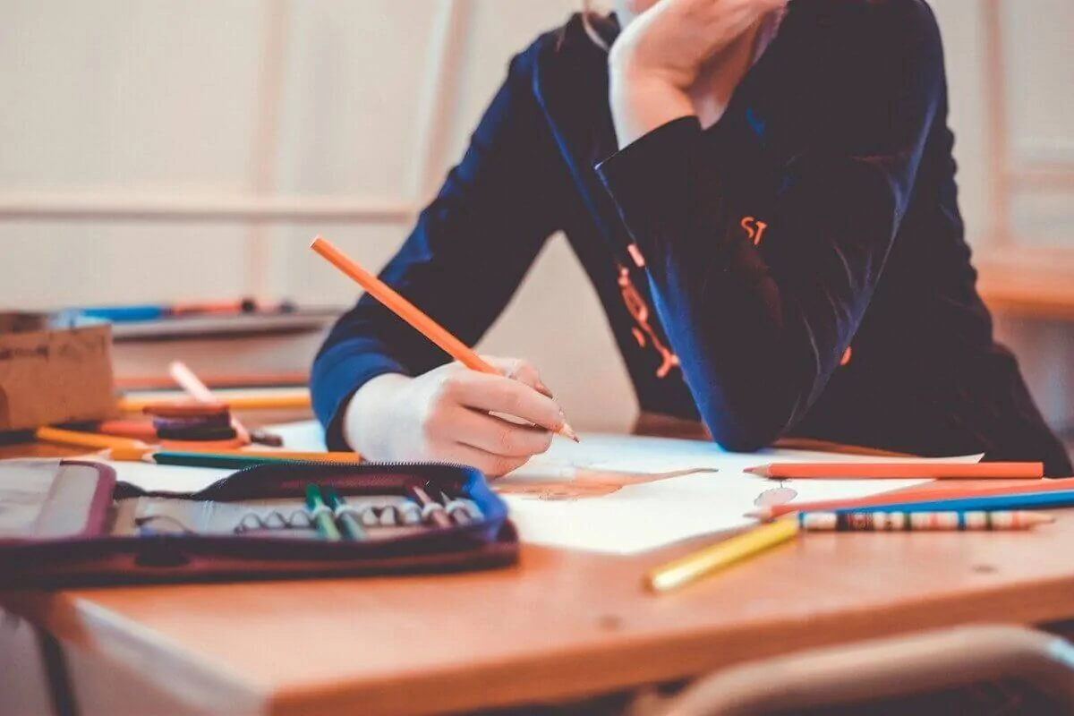 Une personne dessinant à une table avec des crayons, illustrant les mécanismes cognitifs de l'apprentissage sans erreur.