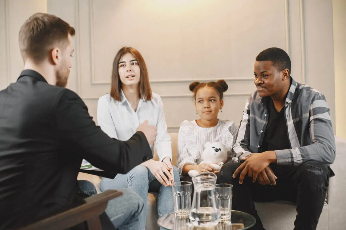 Groupe diversifié de familles et de professionnels assis en rond autour d'un enfant, partageant leur soutien au développement neurologique.