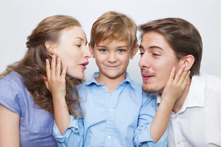 Familia de tres miembros: niño entre dos adultos abrazados en un entorno claro y cálido, reflejando apoyo mutuo en trastornos del neurodesarrollo.
