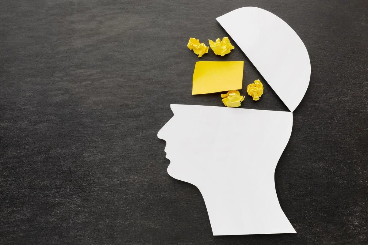 Profil de la tête avec la partie supérieure ouverte ; à l'intérieur il y a du popcorn et un papier jaune, symbolisant l'attention soutenue.