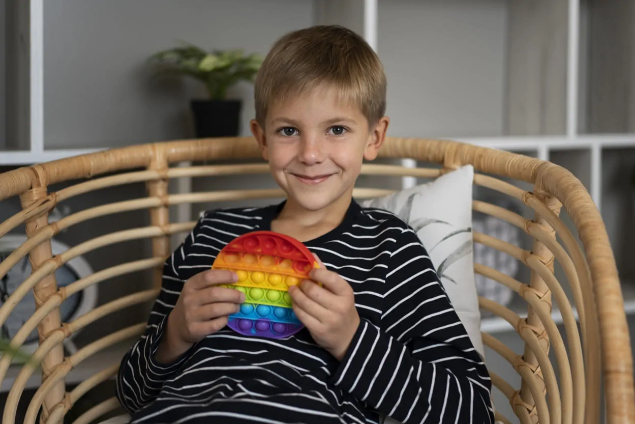 Enfant en consultation de neuropsychologie pédiatrique observe des tests cognitifs aux côtés d'un professionnel dans un cadre clinique.