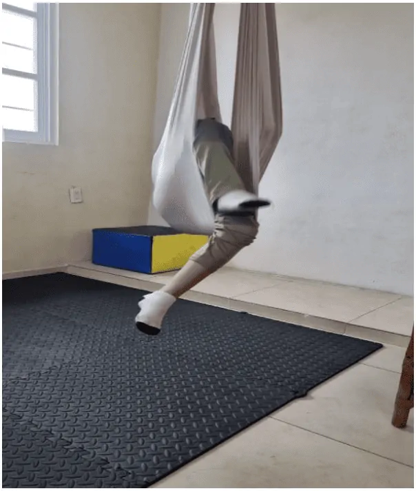 Espace intérieur accueillant avec hamac ; personne partiellement à l'intérieur, seules les jambes avec pantalon clair et chaussettes sont visibles.