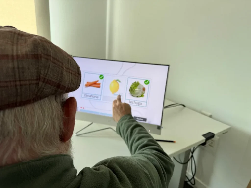 Patient en unité ambulatoire réalise une séance d'aphasie motrice devant un écran interactif avec NeuronUP.