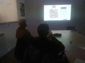 Due persone sedute guardano un proiettore che mostra un grafico di forme e numeri, con cuori, in una sala riunioni.