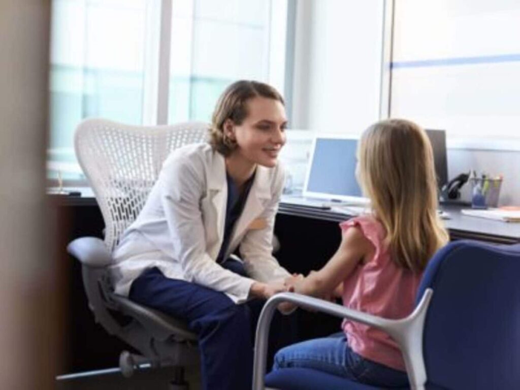 La pediatra, seduta in uno studio luminoso, parla con una bambina