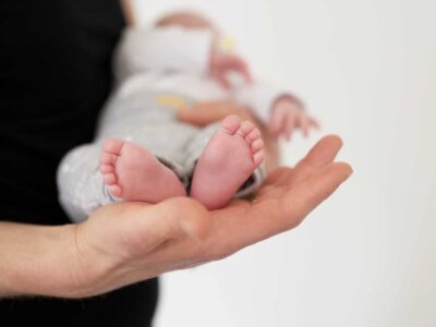 Neuropsicologia clinica nella prematurità e nel neurosviluppo. Piedi di un bambino in braccio a un adulto.