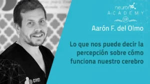 Uomo professionista in conferenza sul cervello, grafici e sfondo con logo Neuron Academy e testo su percezione cerebrale.