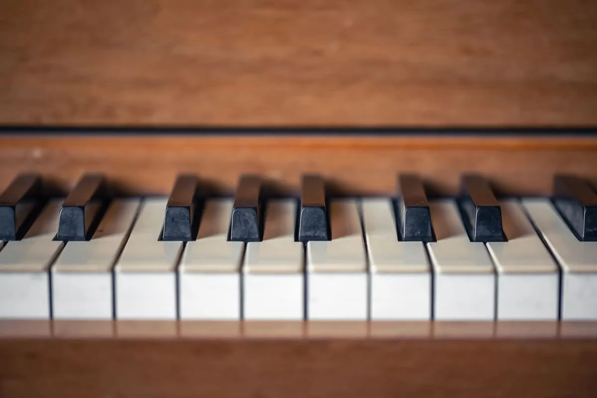 Tasti bianchi e neri di pianoforte su sfondo in legno, associati a un programma di accessibilità musicale per la riabilitazione.
