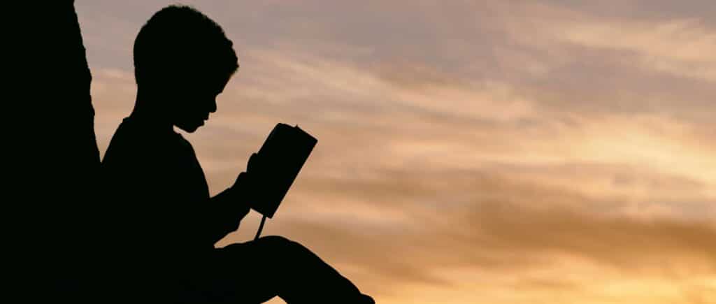 Intervento nei minori con Alte Capacità Intellettuali. Bambino che legge un libro al tramonto