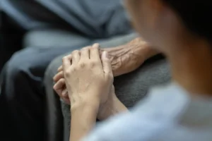 Mani intrecciate di una persona anziana e di una persona più giovane, che simboleggiano il supporto nella riabilitazione cerebrale.