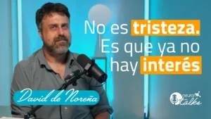 Uomo di fronte a un microfono in un set con luci; testo sull'immagine: 'Non è tristezza. È che non c'è più interesse'.