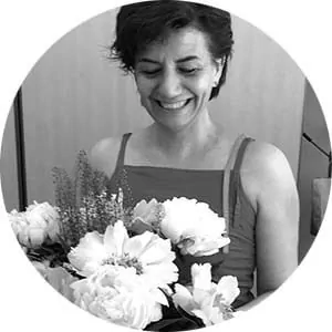 Улыбающаяся Isabel Valle держит букет цветов на конференции об интеллектуальной недостаточности; фон размытый.
