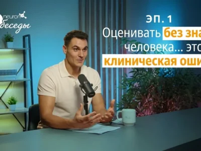 Мужчина сидит перед микрофоном на освещённой сцене во время NeuronUP Talks о нейродегенеративных деменциях.