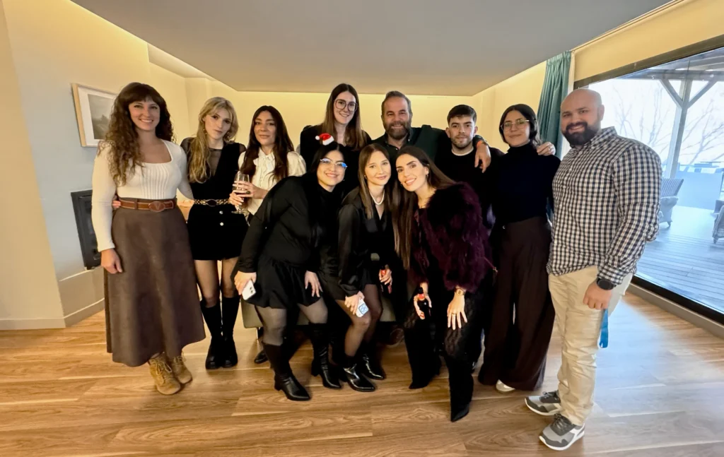 Grupo de personas posando en un interior durante un evento de NeuronUP; vestimenta elegante o casual chic, algunas bebidas y un ambiente festivo.